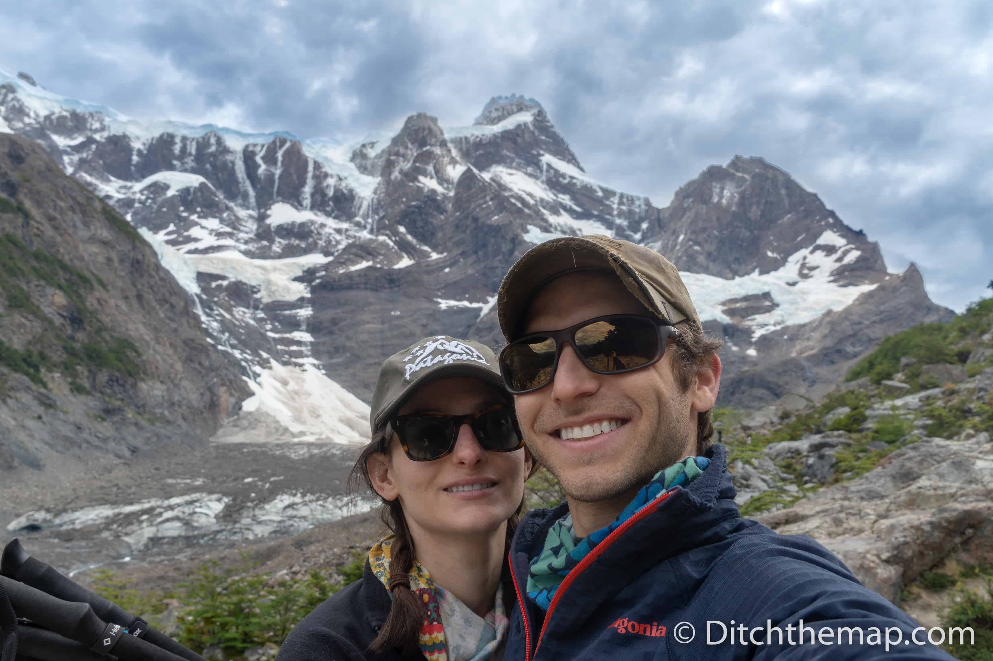 A couple's selfie in front of Torres del Paine Trek snowy mountains