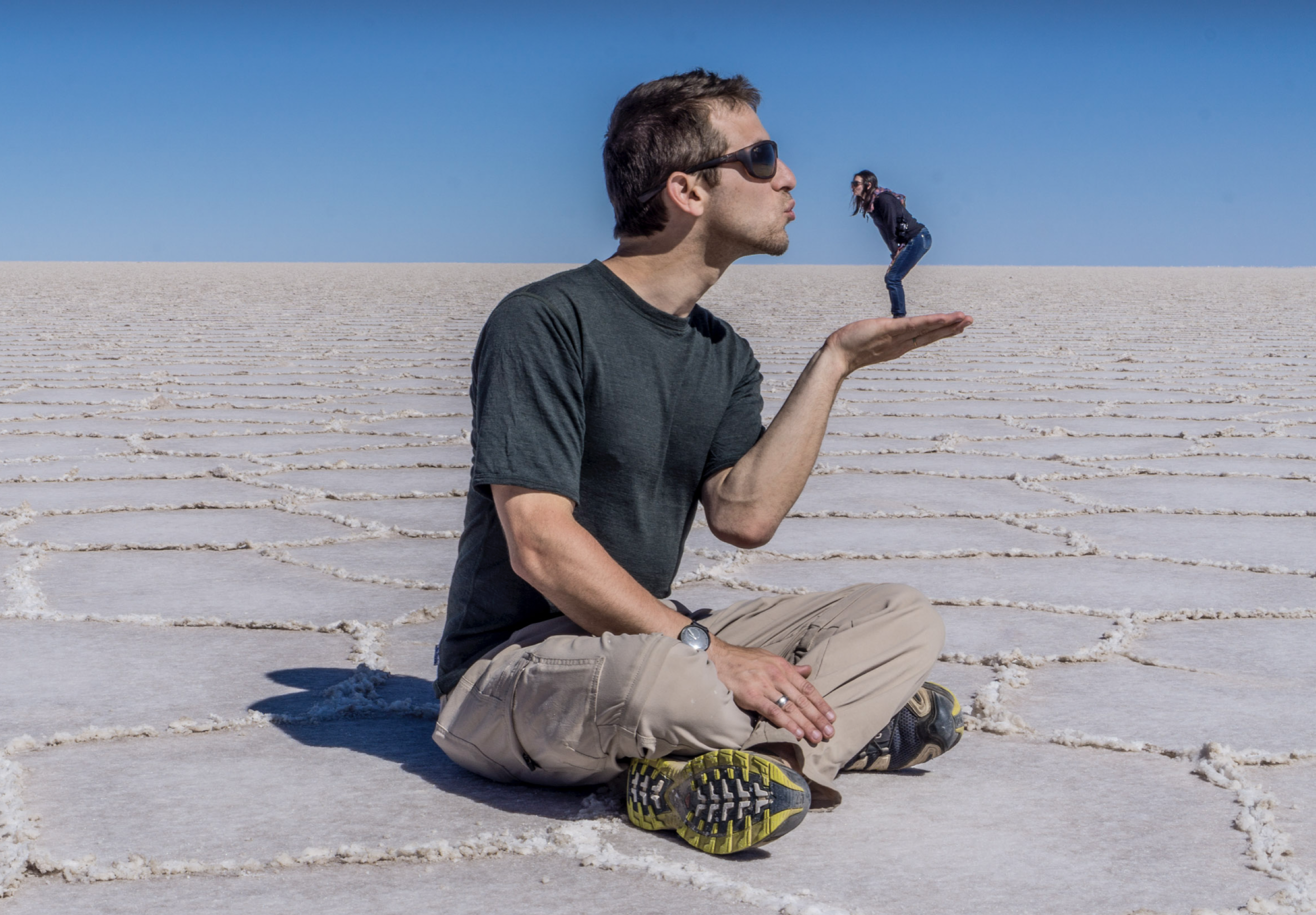 A big man holding and kissing a tiny woman in his hand in the salt lakes