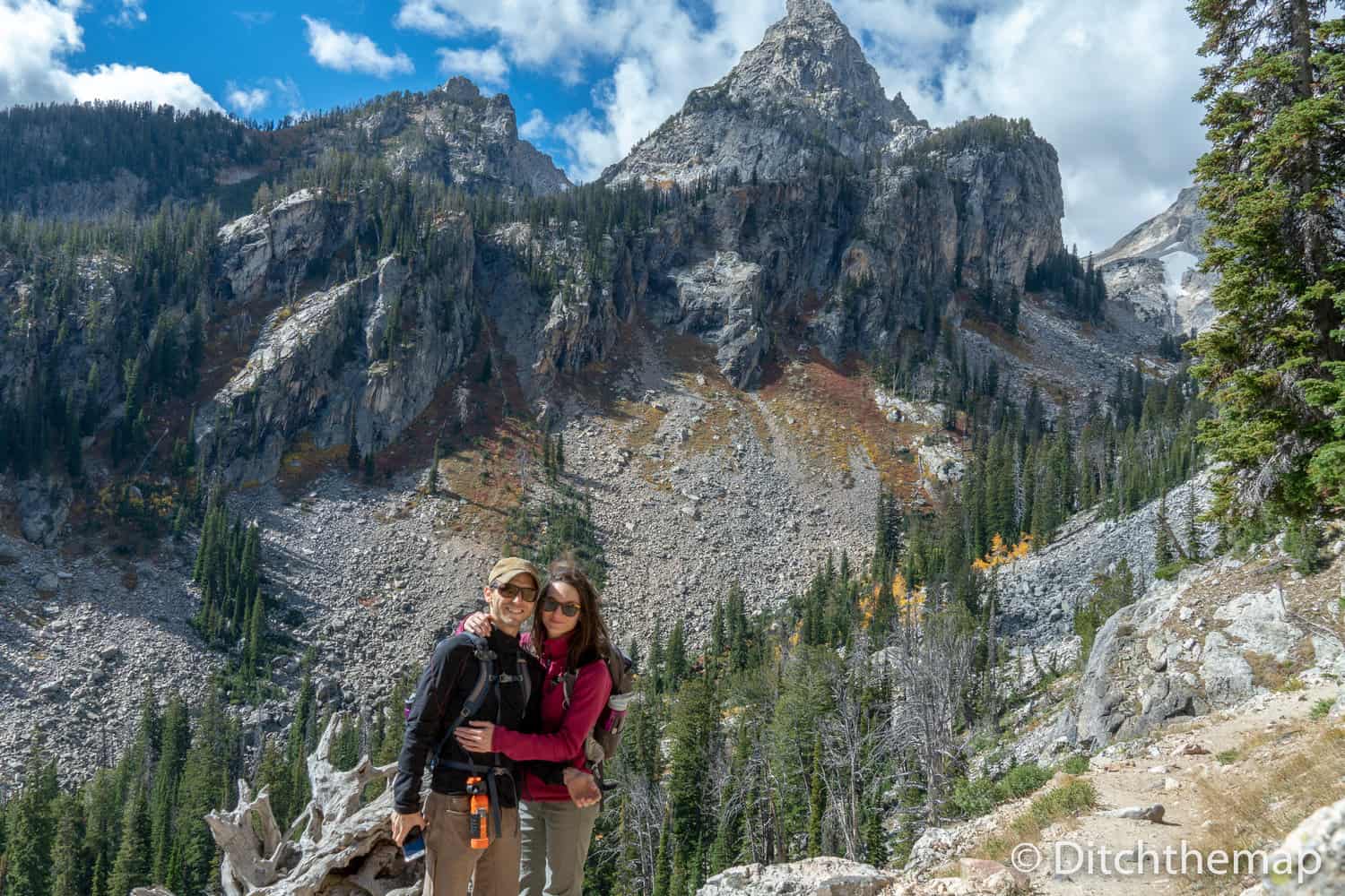 A hiking couple's photo in front of high-peaked mountain, the Grand Tetons